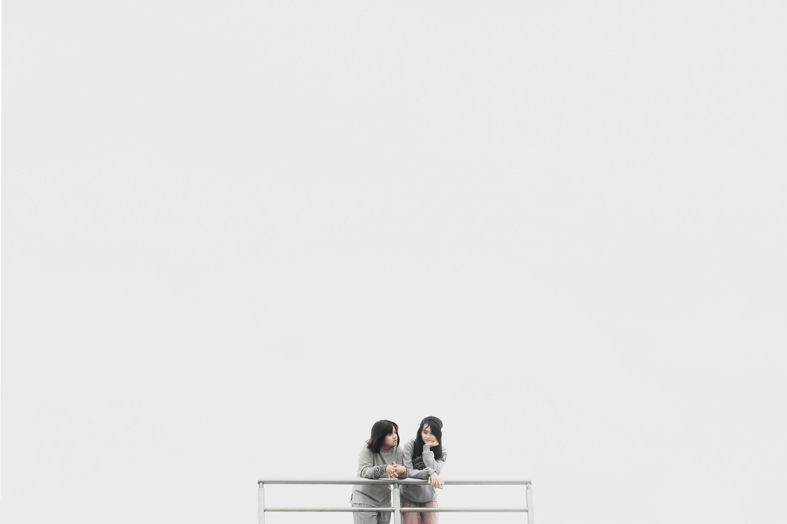 Two Women Leaning On Fence