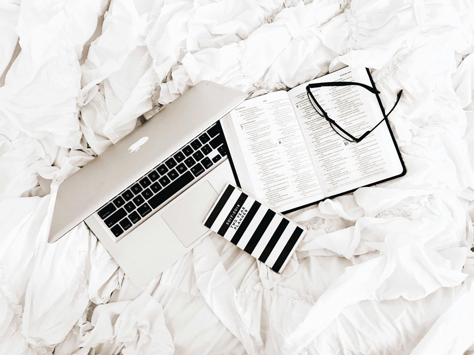 Eyeglasses on Book Beside Macbook