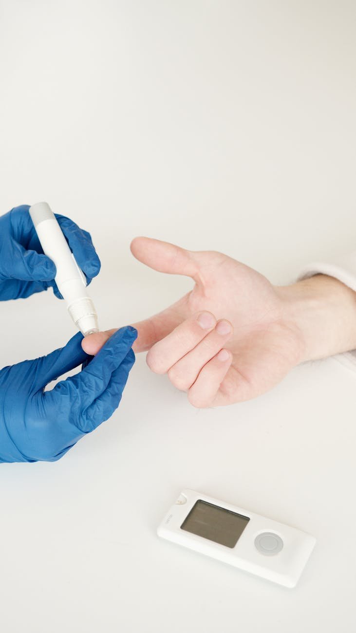 A healthcare professional tests blood sugar with a glucometer and lancet pen in a medical setting.