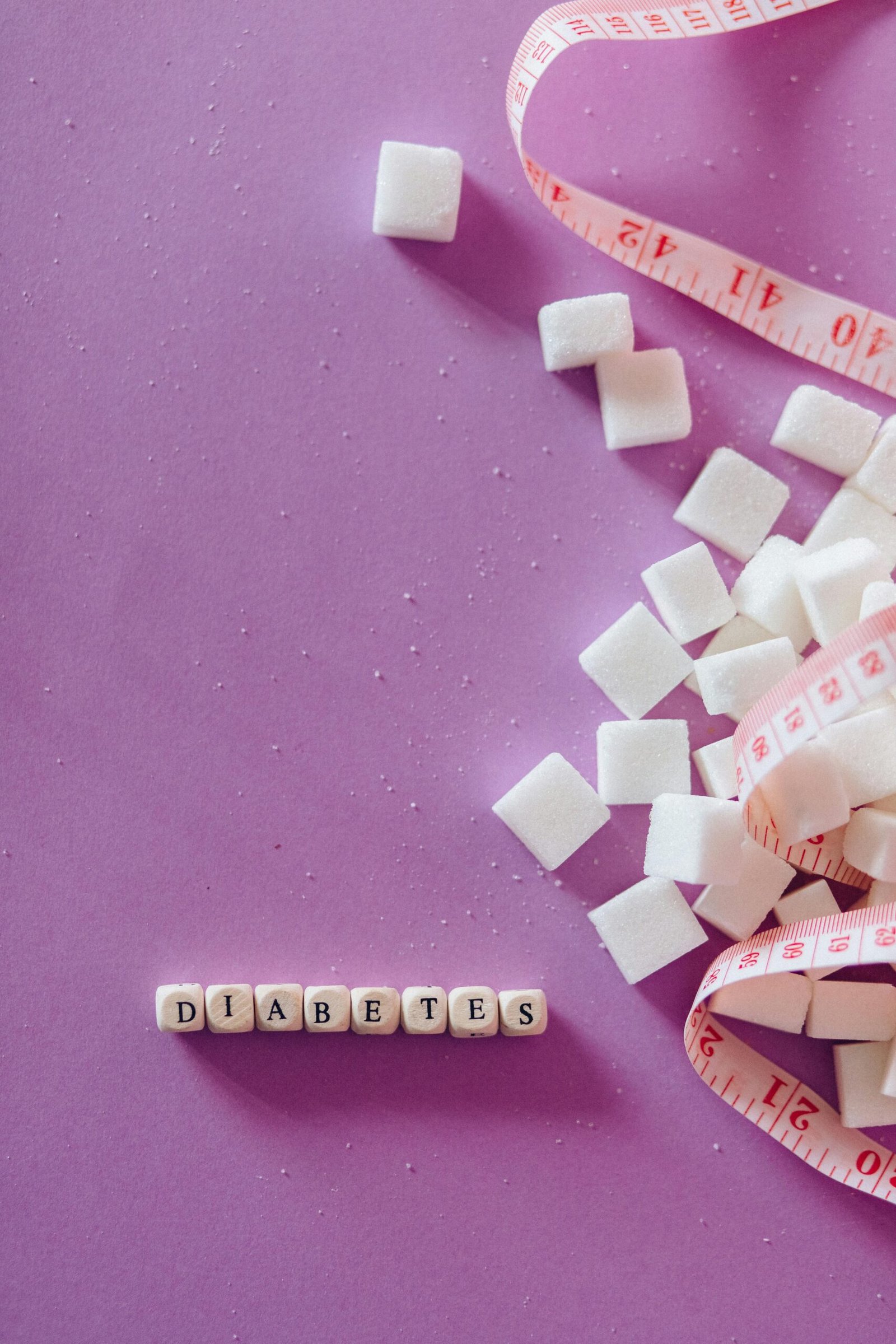 A symbolic image of diabetes awareness with sugar cubes and a tape measure on a pink background.