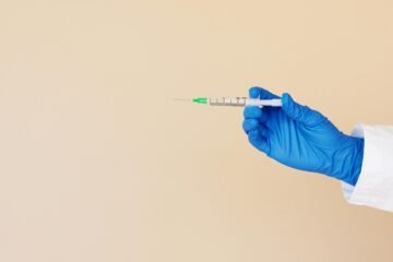 Unrecognizable medical professional holding a syringe, ready for injection.