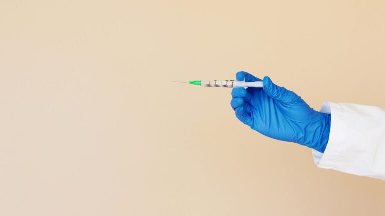 Unrecognizable medical professional holding a syringe, ready for injection.