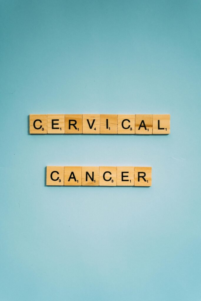 Wooden tiles spell 'Cervical Cancer' on a light blue background, raising awareness.
