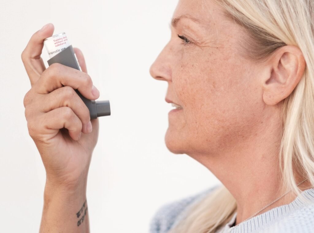 Middle-aged woman using an asthma inhaler to alleviate breathing difficulties.